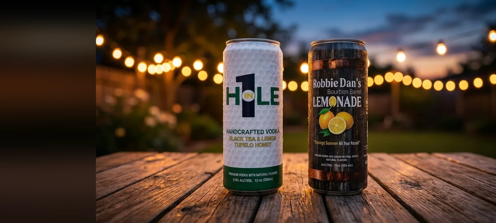 Cans of Hole in 1 and Robbie Dan’s on a table at dusk under string lights.